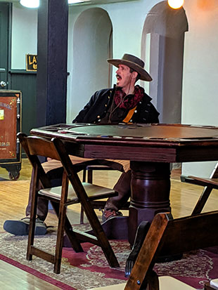 Another image of a cowboy sitting at the gambling table.